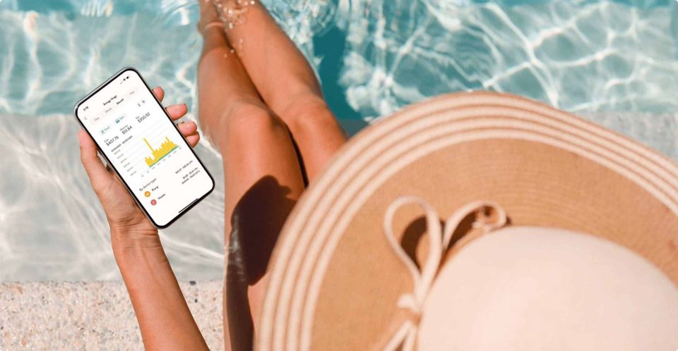 person checking automated pool settings from phone while in the pool